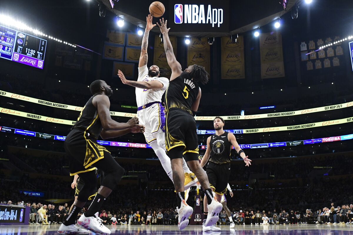 Lakers forward Anthony Davis lofts a shot over Warriors forward Kevon Looney.
