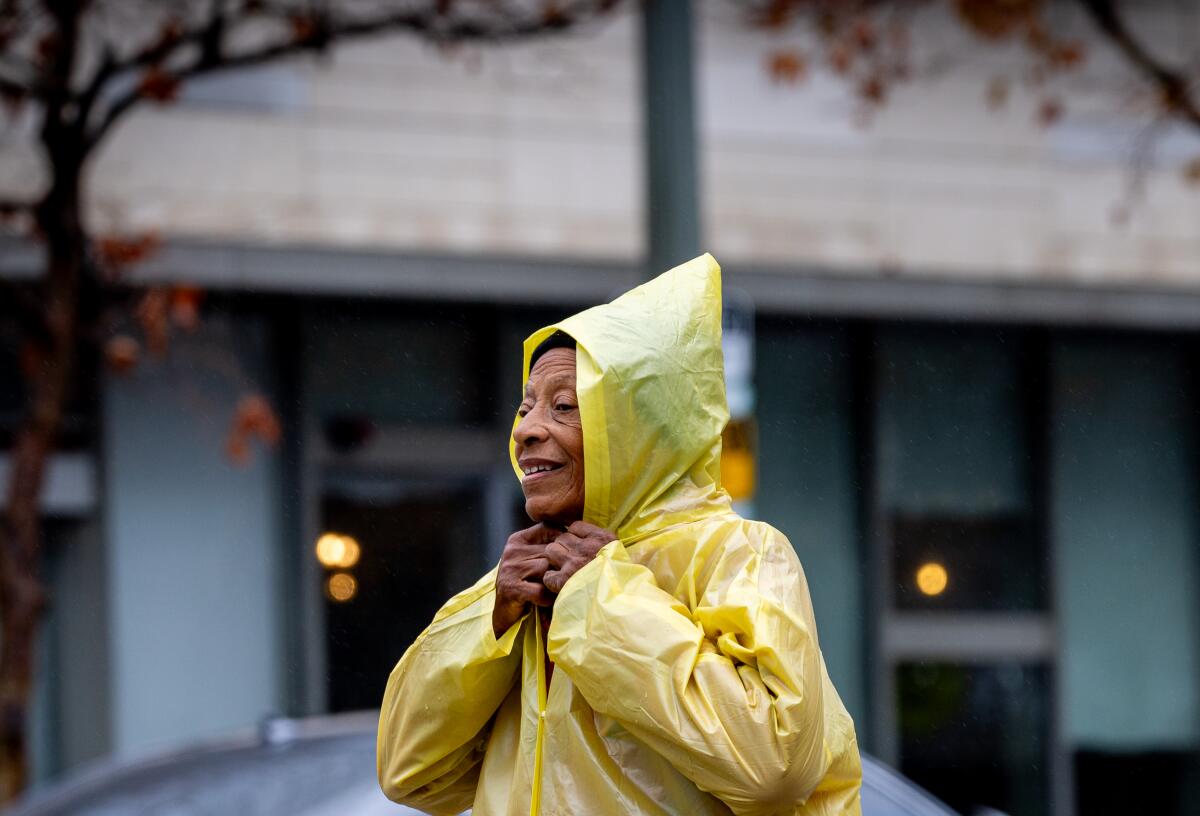 A pedestrian tightens a rain covering amid showers in downtown Los Angeles.