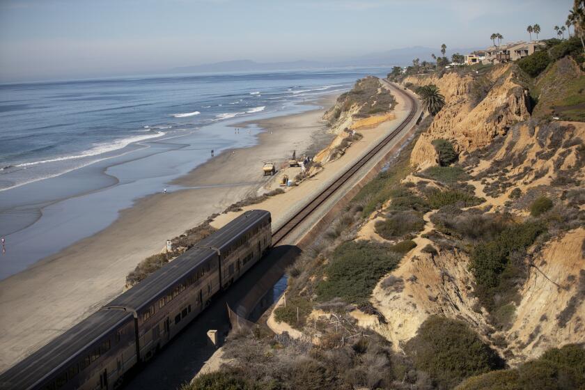 Del Mar, California - November 15: Amtrak Pacific Surfliner passes as construction crews strengthen a wall at the bluff on Monday, Nov. 15, 2021 in Del Mar, California. (Ana Ramirez / The San Diego Union-Tribune)