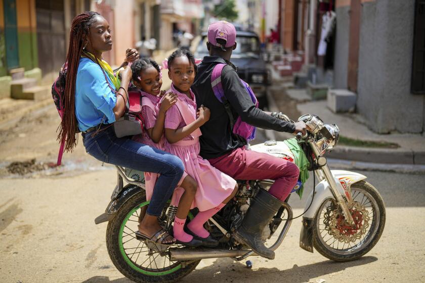 People ride on a motorcycle in Cap-Haitien, Haiti, Wednesday, April 17, 2024. (AP Photo/Ramon Espinosa)