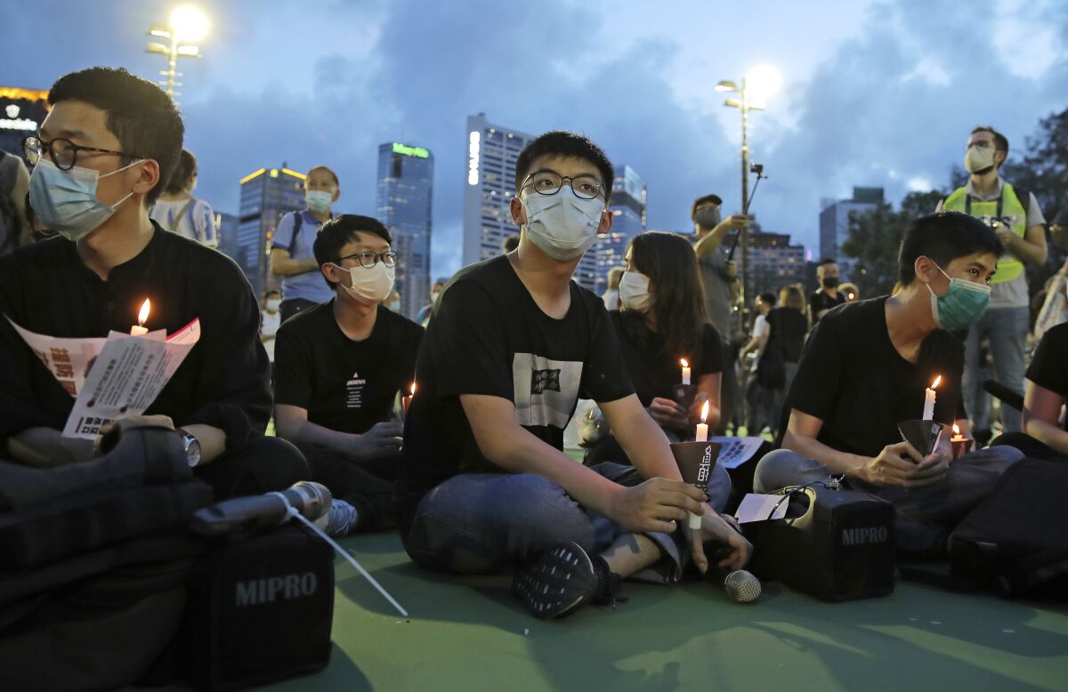 In this June 4, 2020, photo, democracy activist Joshua Wong, center, and Nathan Law, left, hold candles during a vigil to remember the victims of the 1989 Tiananmen Square Massacre at Victoria Park in Hong Kong. Wong will face an additional 10 months in jail for participating in an unauthorized Tiananmen vigil held last year to commemorate the 1989 crackdown on protesters in Beijing, as Hong Kong authorities continue tightening control over dissent in the city. (AP Photo/Kin Cheung)