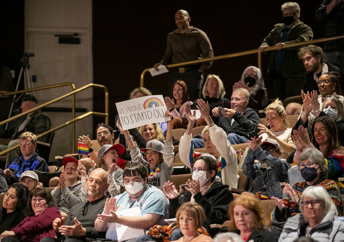 Nico Osborne, center, with his six siblings and moms Sal and Lena Osborne, right, holds up a sign during council meeting.