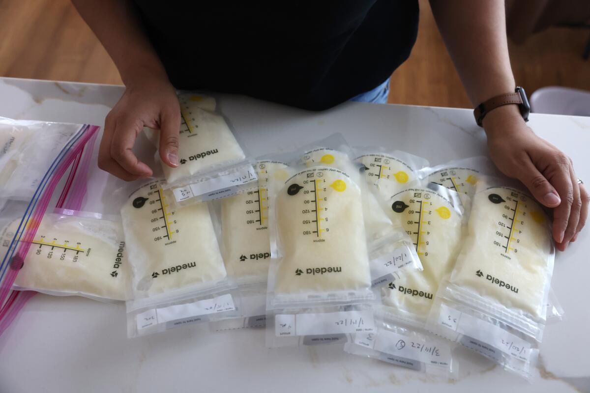 A woman looks at bags of breast milk on a counter.