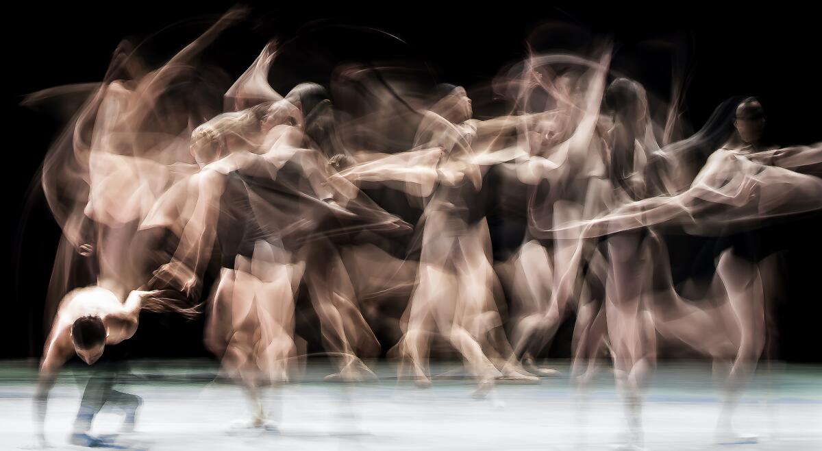 A blurred image of dancers in motion on stage. 