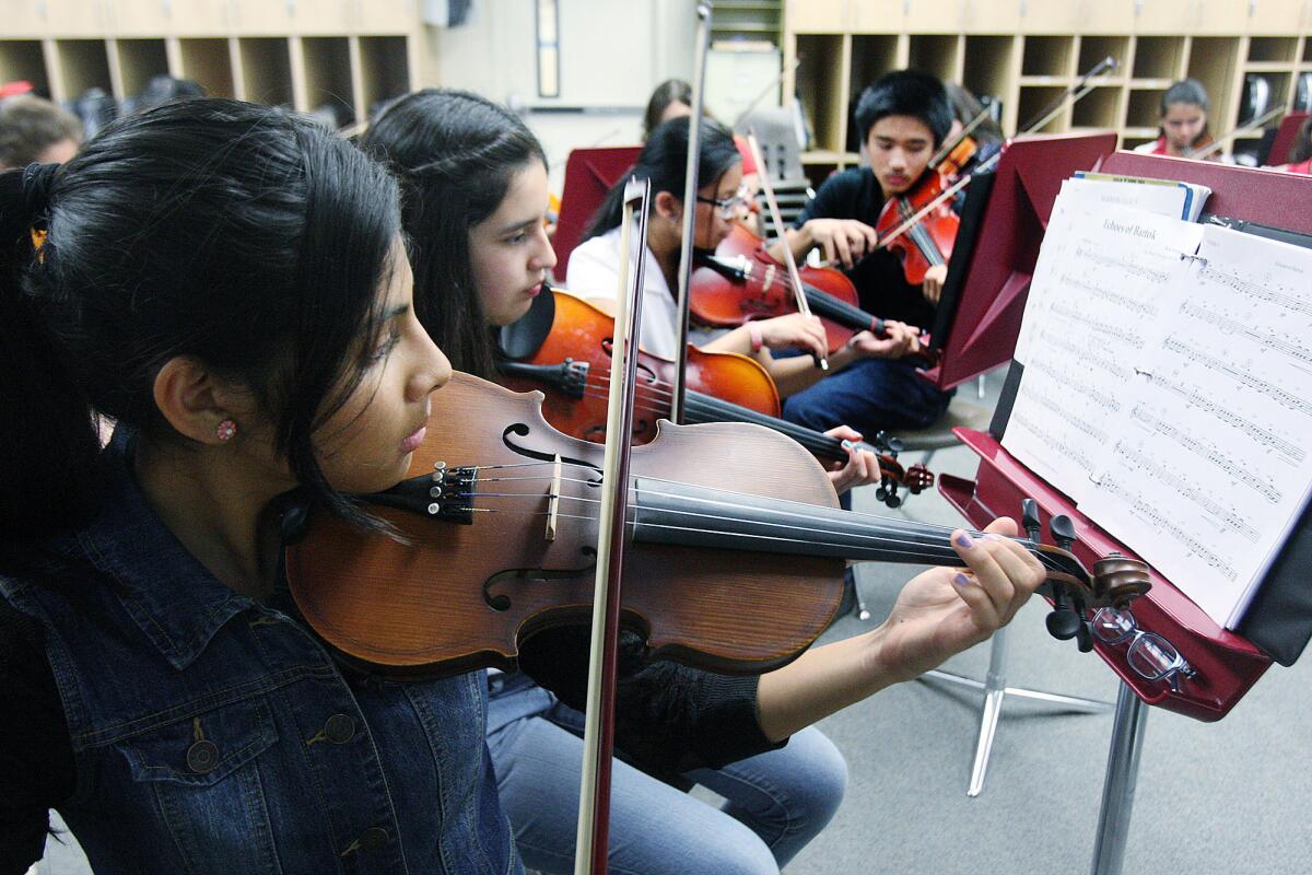 Mary Angel Bello, 14, Melissa Martinez, 14, Melina Villamor, 13, and Lorenzo Ledesma, 13, play violin during rehearsal in the instrumental music class of music teacher Frank Fox at Roosevelt Middle School on Thursday, April 10, 2014. Fox filled out a survey which lead to the recognition of the school district as one of 376 districts in the country for "Best Communities for Music.
