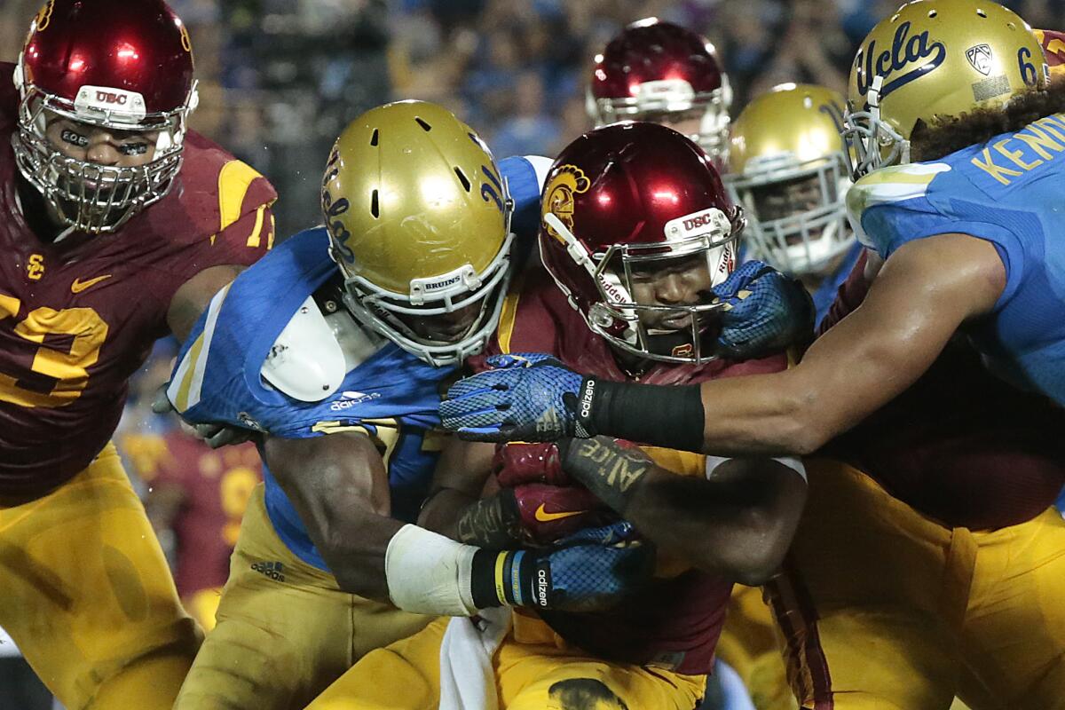 USC tailback Javorius Allen is wrapped up by UCLA lineman Owamagbe Odighizuwa in November.