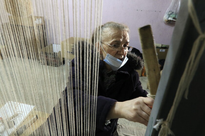 Hate Ora, 64, or 'Aunt Hate' as everyone knows her, weaving a carpet in Kukes town, northeastern Albania, Friday, March 12, 2021. Albania once had 13 former state-run factories that produced carpets, rugs, fez hats, felt folk costumes and other handicrafts. Kukes, a town northeast of the capital, Tirana, alone employed more than 1,200 women as weavers. When the country's communist era ended in 1990, the local factory closed. (AP Photo/Hektor Pustina)