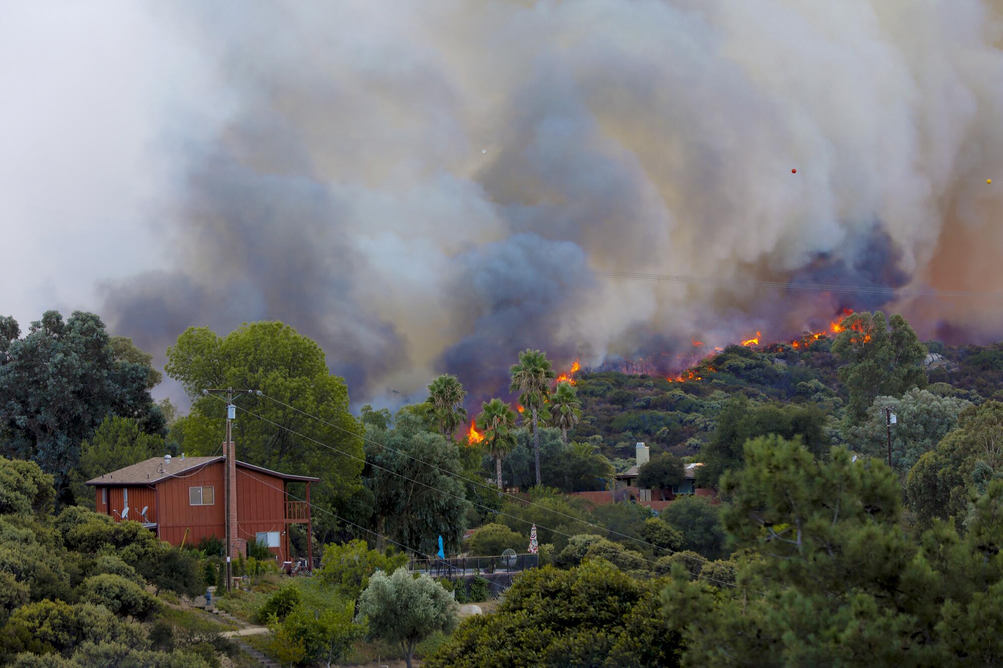 A wildfire burns near a home.