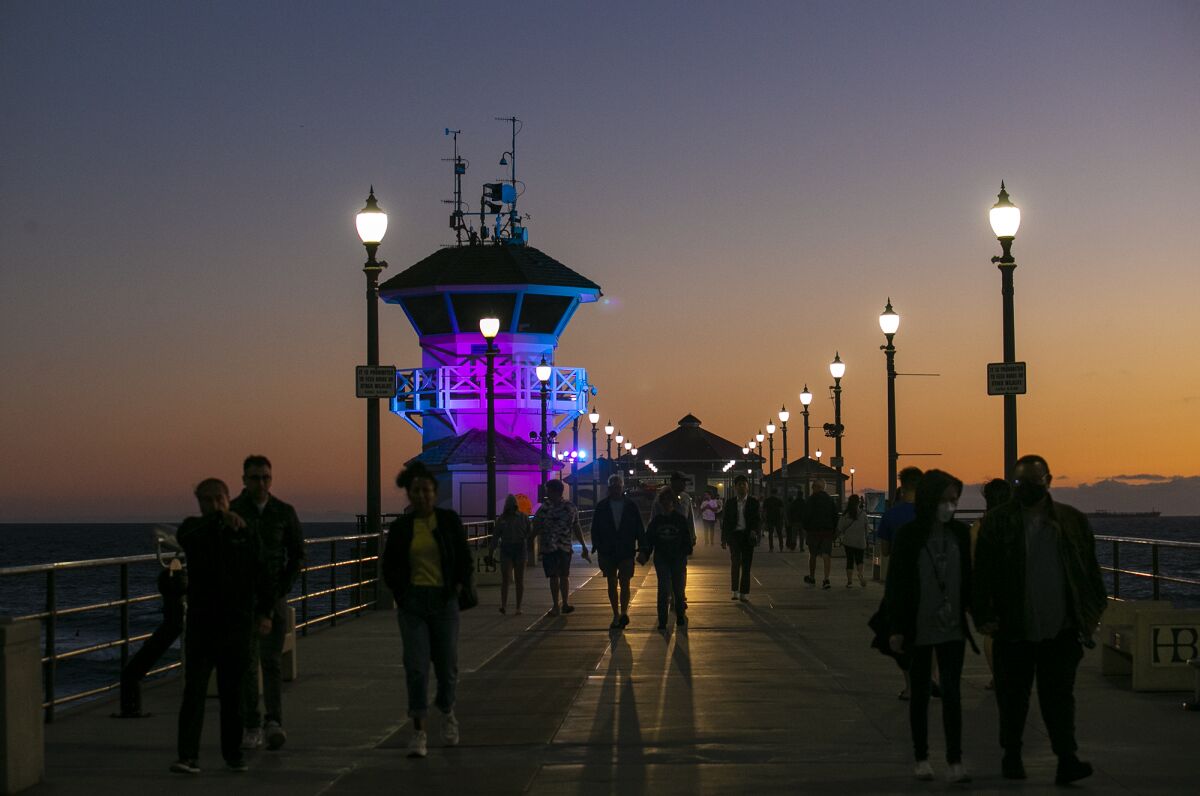 Visitors walk along the Huntington Beach Pier Tuesday evening in Huntington Beach.