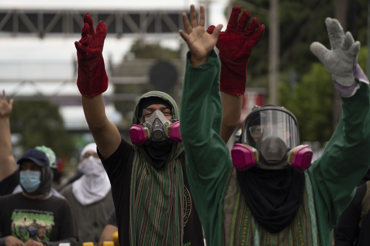 Estudiantes encapuchados desafían a la policía como parte de una protesta antigubernamental en Guatemala