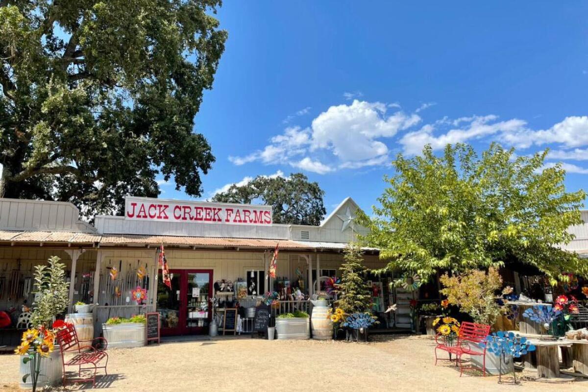 A country store with a sign that reads "Jack Creek Farms" and colorful benches outside.
