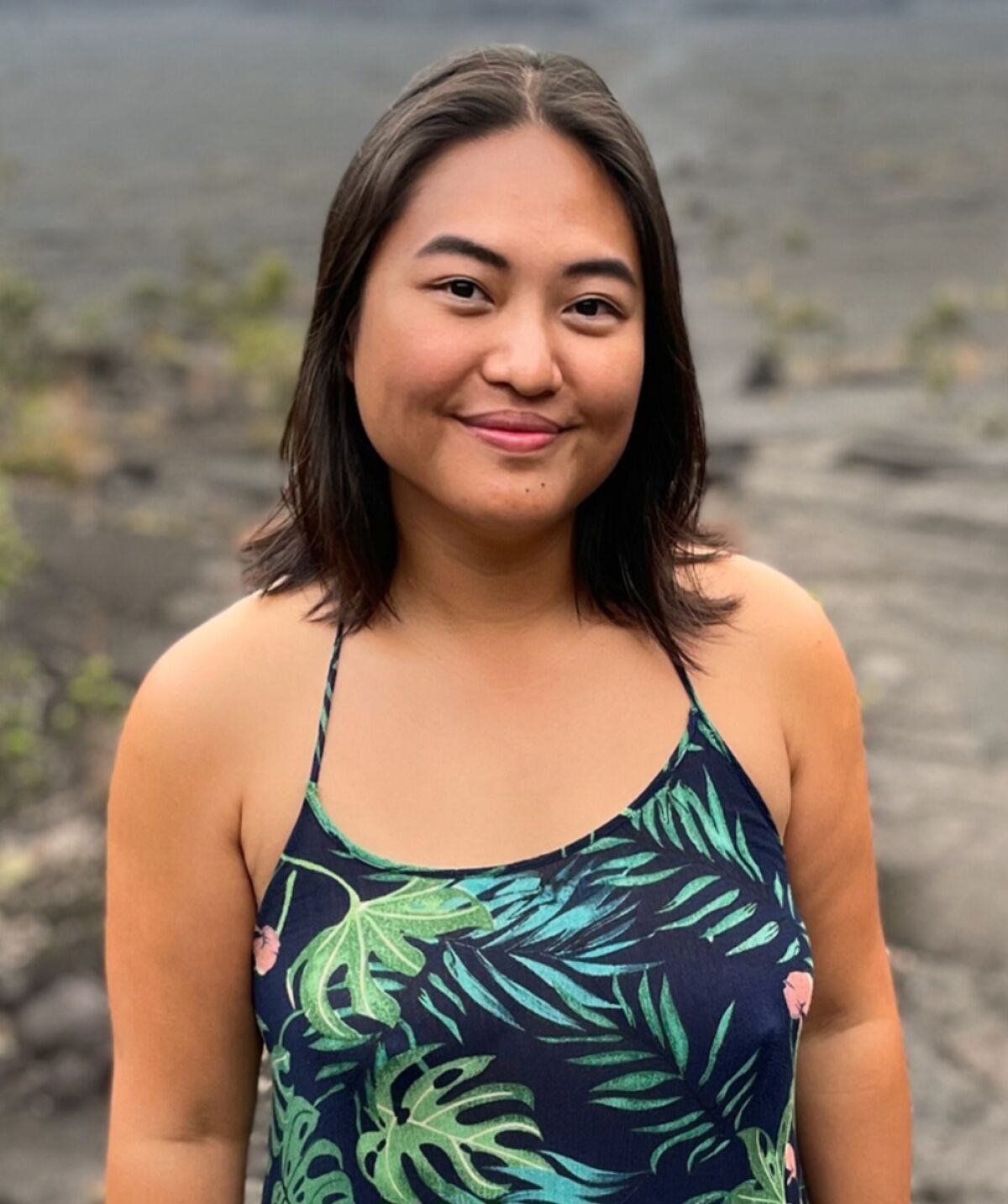 A woman in a tank top poses outdoors.