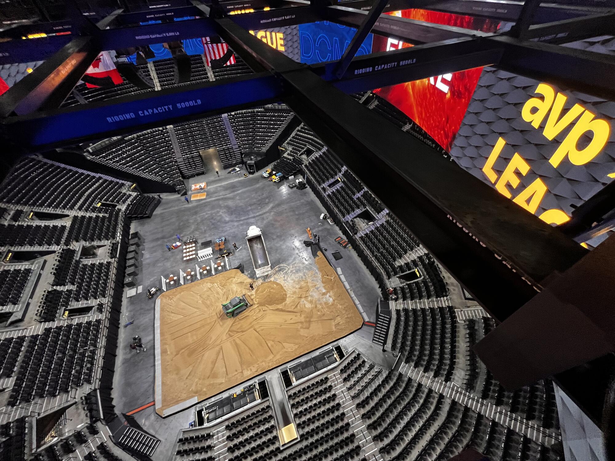Workers cover the floor of the Intuit Dome with sand ahead of an AVP league event.