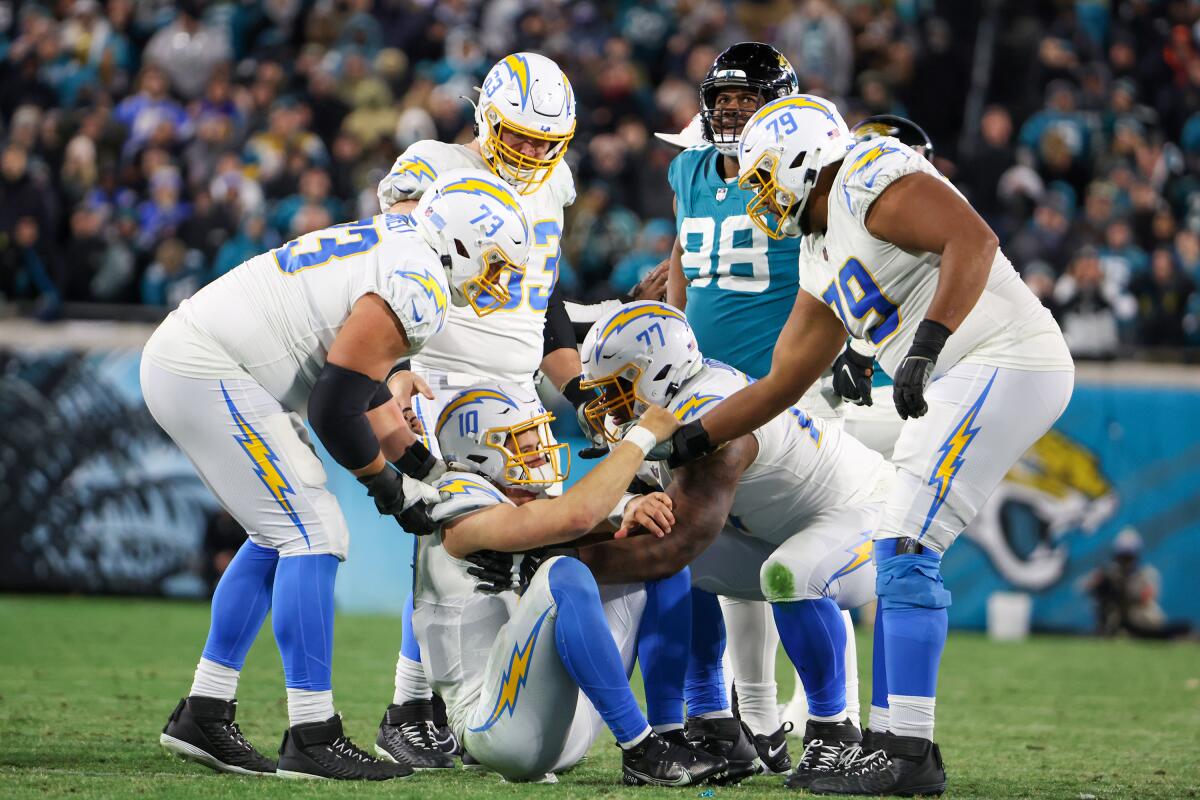  Chargers help quarterback Justin Herbert (10) to his feet after getting knocked down.