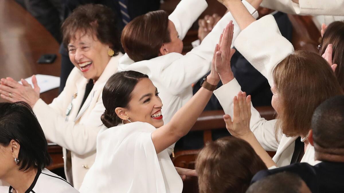 Rep. Alexandria Ocasio-Cortez (D-N.Y.), center, and other lawmakers at President Trump's State of the Union address at the U.S. Capitol on Tuesday. Some female lawmakers chose to wear white to the speech in solidarity with women and a nod to the suffragette movement.