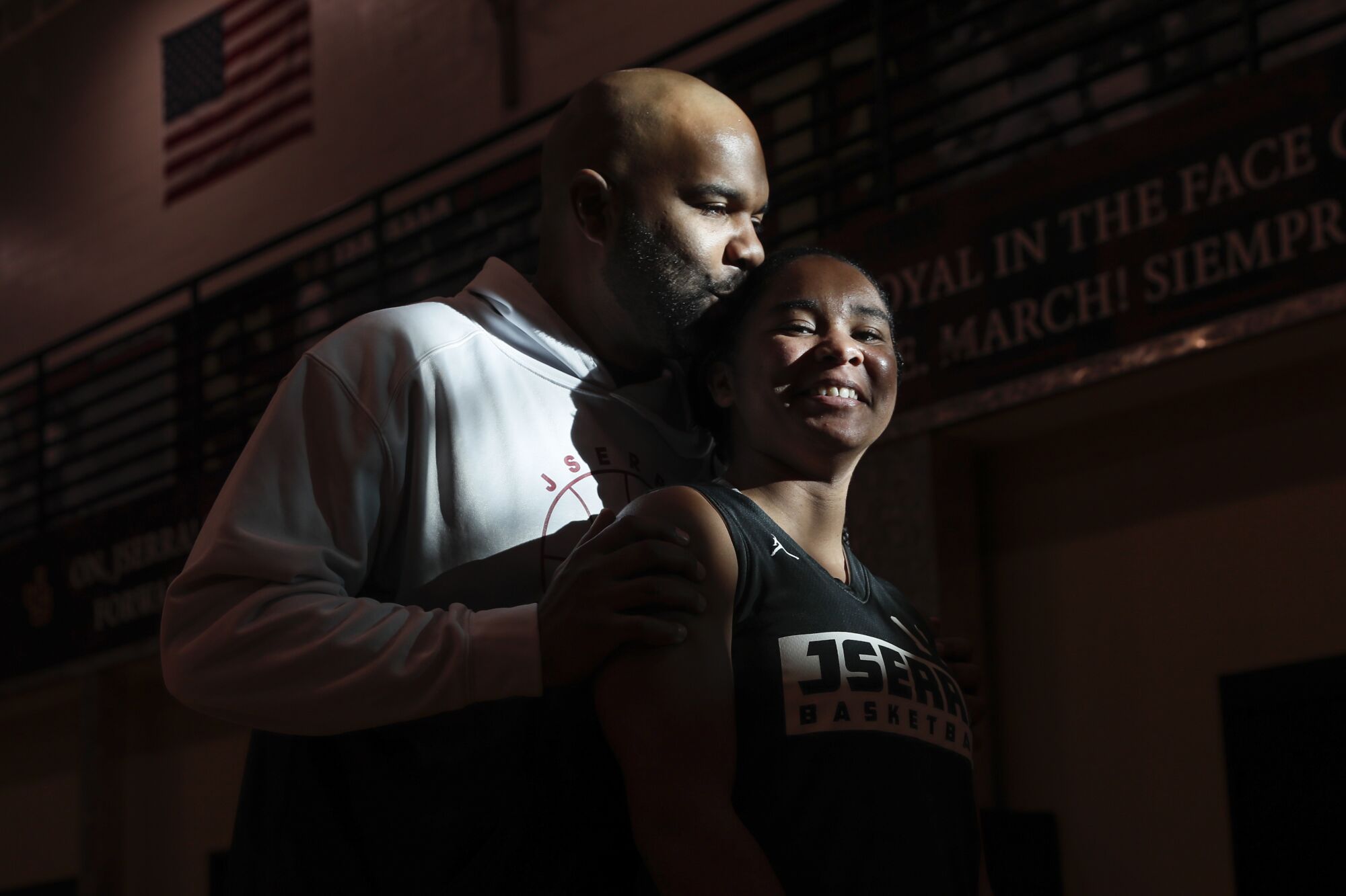 JSerra girls' basketball coach Geoffrey Clayton gives a kiss to he head of daughter Jailynn  while posing for a photo.