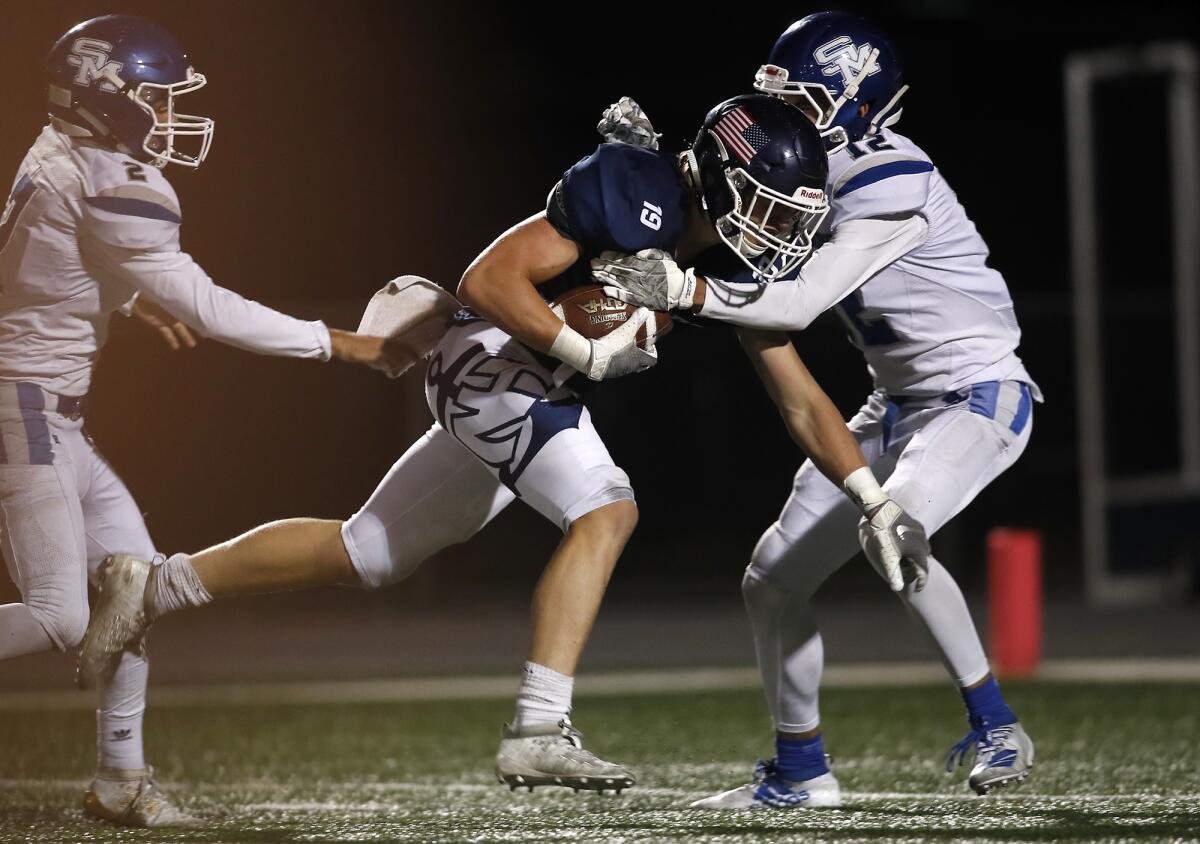 Newport Harbor receiver Aidan Goltz (19) beats San Marino's Niko Mavridis, left, and Trond Grizzell as he completes a 22-yard touchdown catch in the first quarter on Friday.