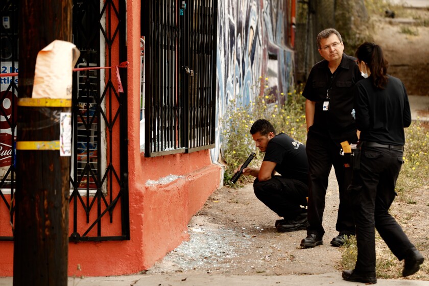  LAPD investigators from Force Investigation Division inspect a building with bullet holes near the scene of an officer involved shooting at Alhambra Ave and Belleglade in the El Sereno neighborhood