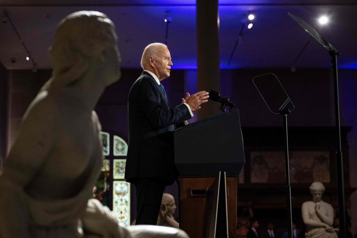 President Biden speaking, with a statue in the foreground