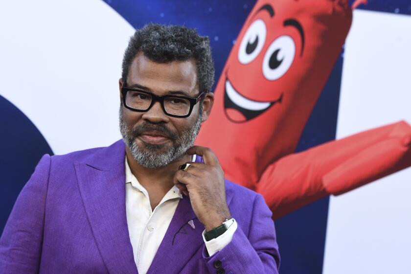 A man with a beard and glasses posing in a purple suit