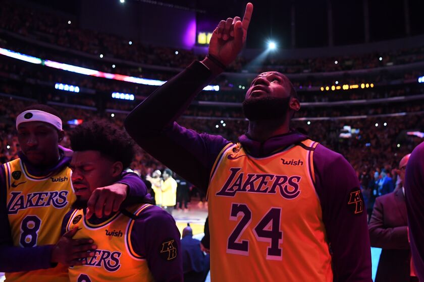 LeBron James points to the sky as Kentavious Caldwell-Pope comforts Quinn Cook before a game in which the Lakers honored Kobe Bryant at Staples Center.