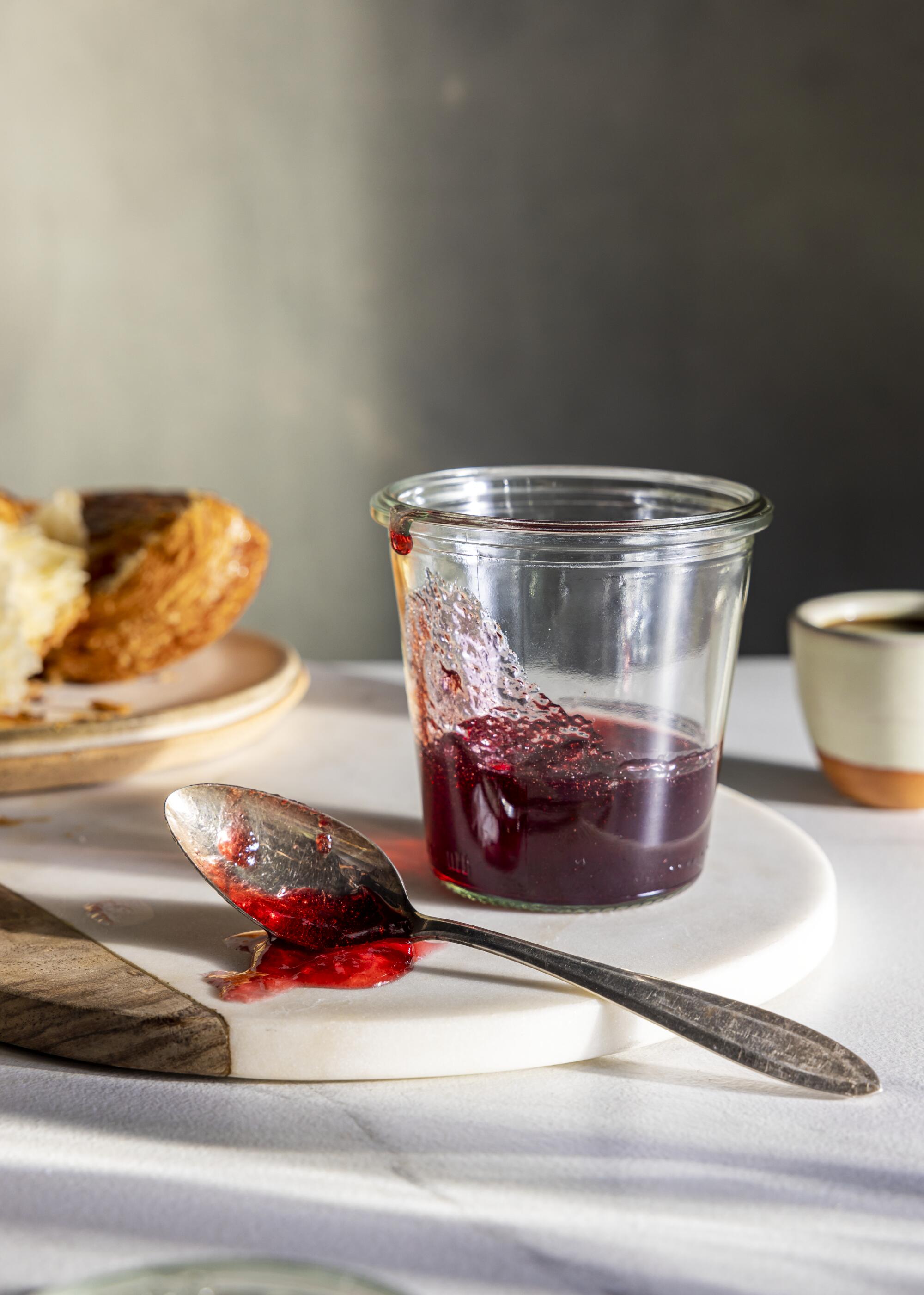 Blackberry jelly on a spoon and in a clear cup.