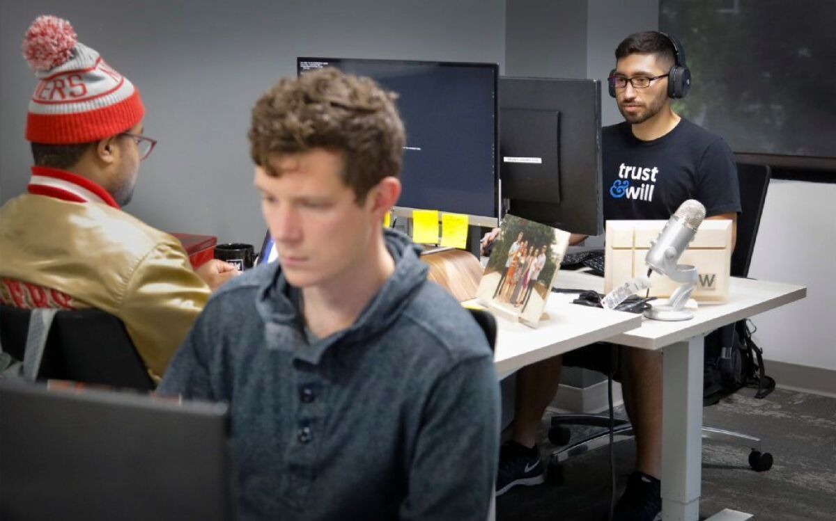 Junior developers at Trust & Will, Philip Taft-Dick, foreground, Taylor Lake, left, back to camera, and Devin Ledesma, right. The startup has a space at the Little Italy coworking space Downtown Works