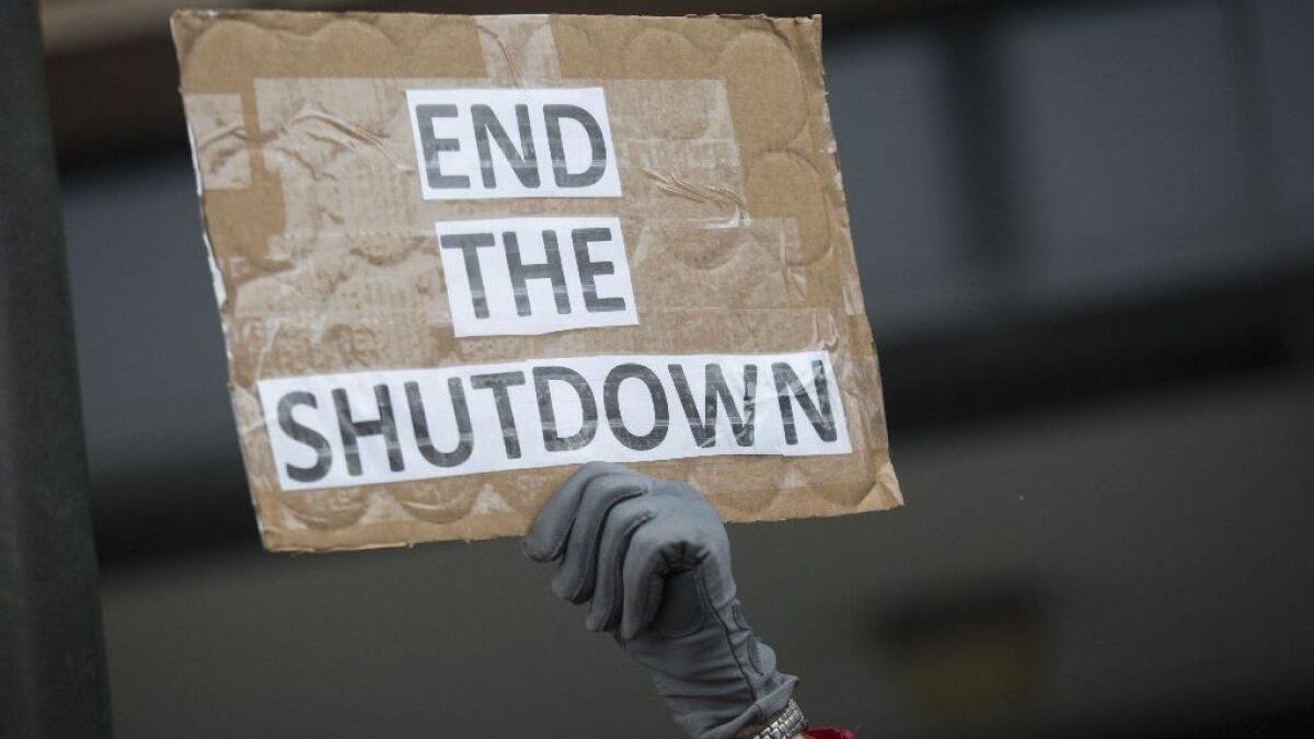 A demonstrator holds a sign protesting the government shutdown at the James V. Hansen Federal Building in Ogden, Utah, on Jan. 10.