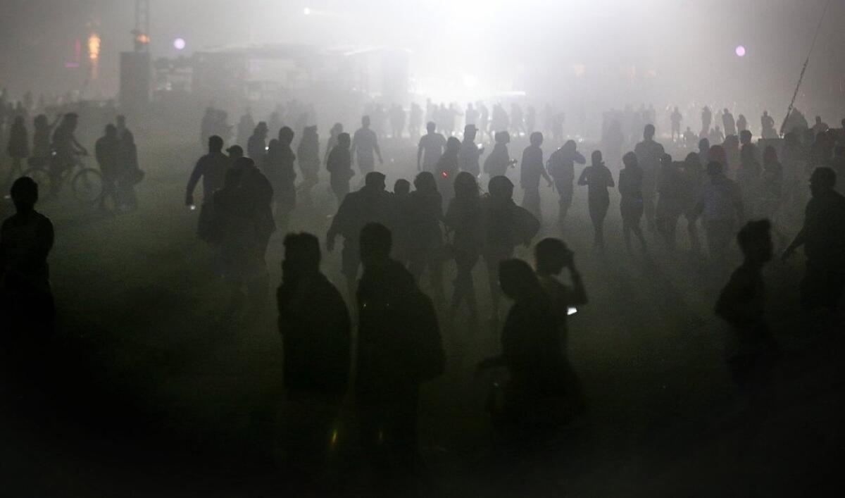 Patrons trudge through a haze of sand and dust during high winds Saturday night at the Coachella Valley Music and Arts Festival in Indio.