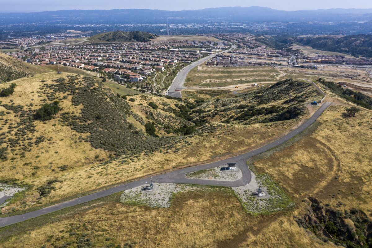 Aerial view of scrubby hills and a community of houses.