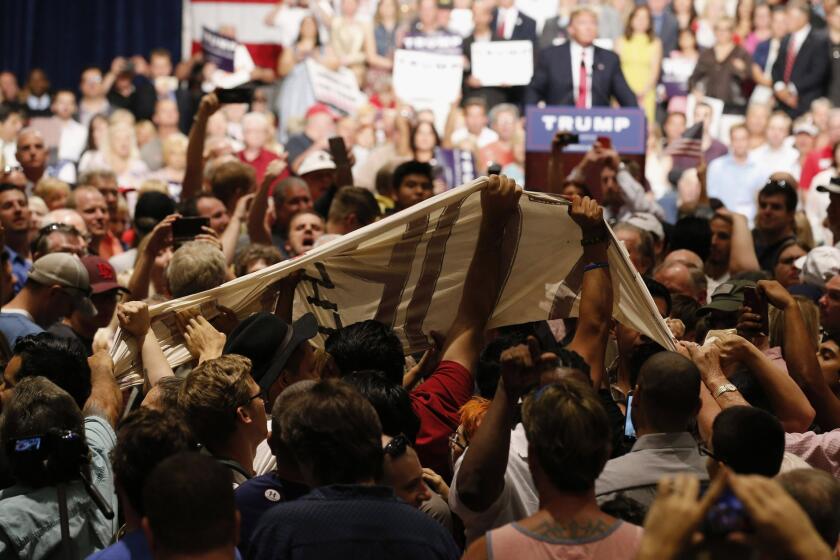 Supporters of Republican presidential candidate Donald Trump pull down a banner from immigration rights protesters as Trump speaks in Phoenix last summer.