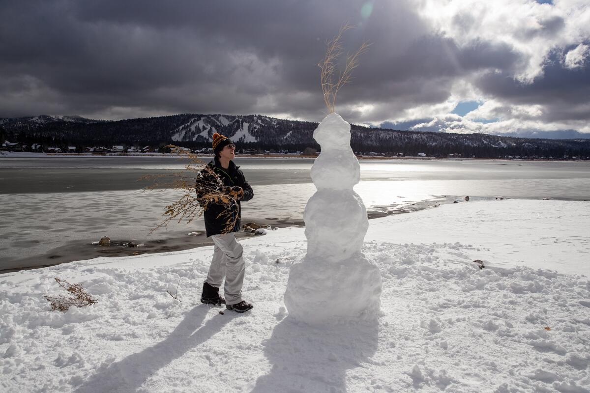 A man next to a snowman in Big Bear.
