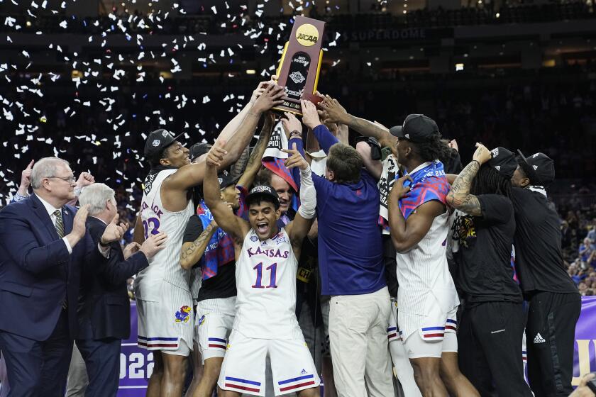 Kansas celebrates with the trophy after their win against North Carolina in a college basketball game.