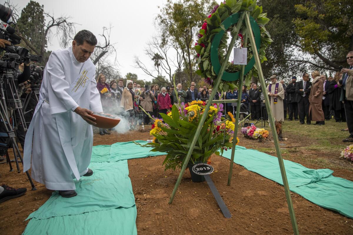 Chaplain Orlando Rubio blesses the grave with incense on Wednesday.