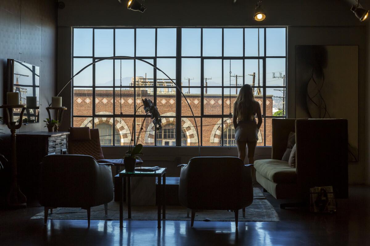 A person in a loft looks out a big window.