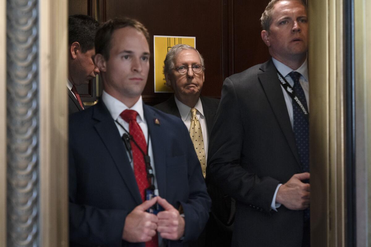 Senate Minority Leader Mitch McConnell rides in an elevator with security on Capitol Hill