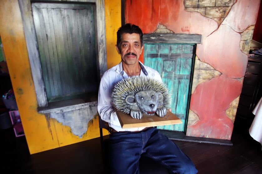 Artist Raul Monterroso, of San Fernando, holds a porcupine that he carved from recycled wood.