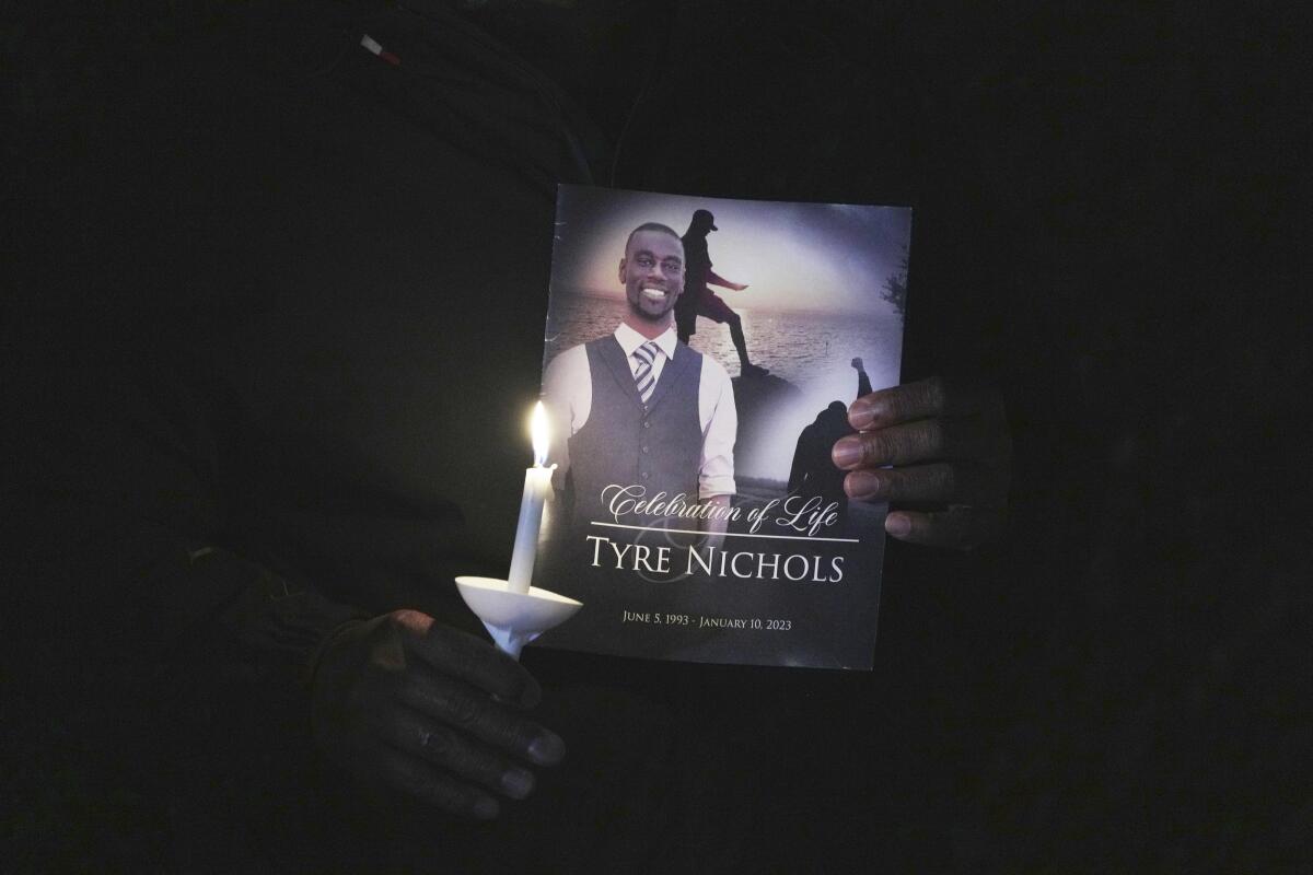 Closeup of a candle and flier held by a mourner at a vigil for Tyre Nichols on Jan. 7, the anniversary of his death