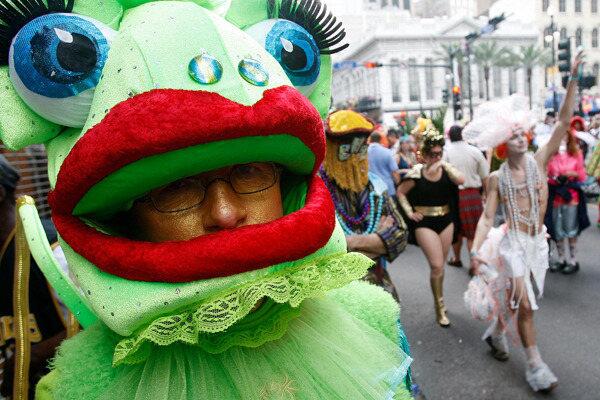 A reveler wearing a frog costume watches the Society of St. Ann parade on Mardi Gras.