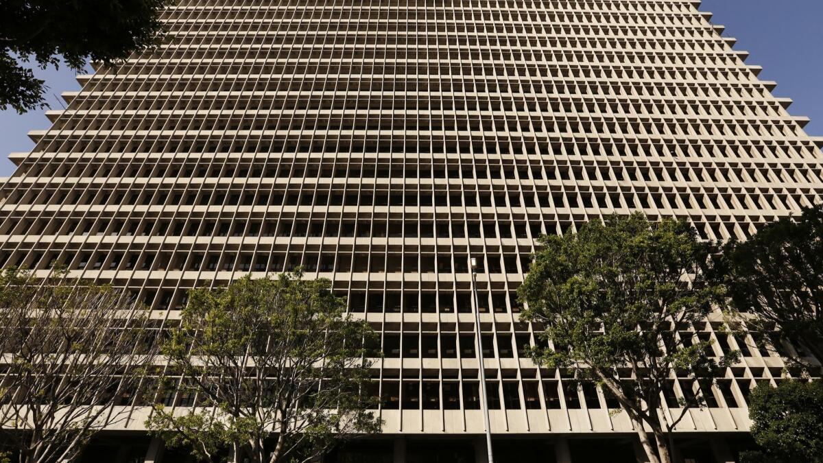 A many-storied building with close packed windows in a grid pattern rises into the sky