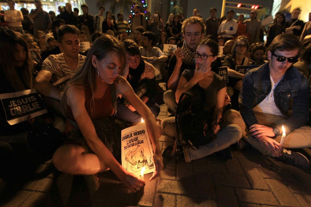 epa04550350 Participants light candles and hold placards that read Je Suis Charlie (I'm Charlie) as they hold a vigil for the killed people of the Paris Charlie Hebdo headquarters terror attack, in Lima, Peru, 07 January 2015. Masked gunmen with automatic rifles killed 12 people at the Paris headquarters of satirical French magazine Charlie Hebdo, which had angered Muslims two years ago by publishing cartoons of the prophet Mohammed. EPA/Paolo Aguilar ** Usable by LA, CT and MoD ONLY **