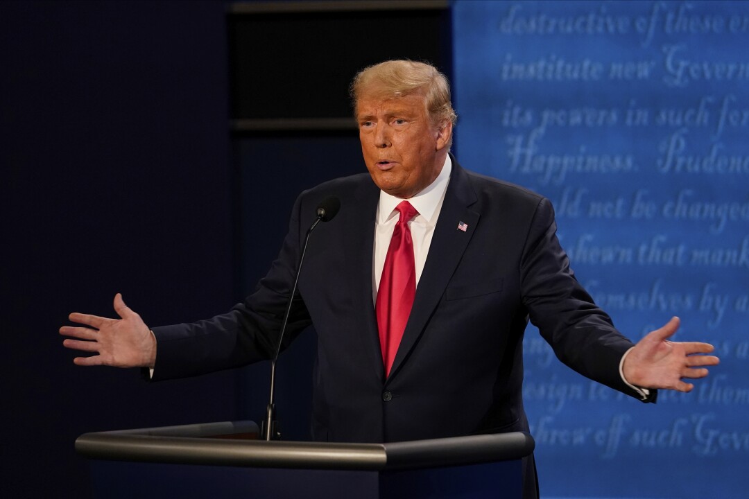 President Trump stretches both arms out as he speaks onstage