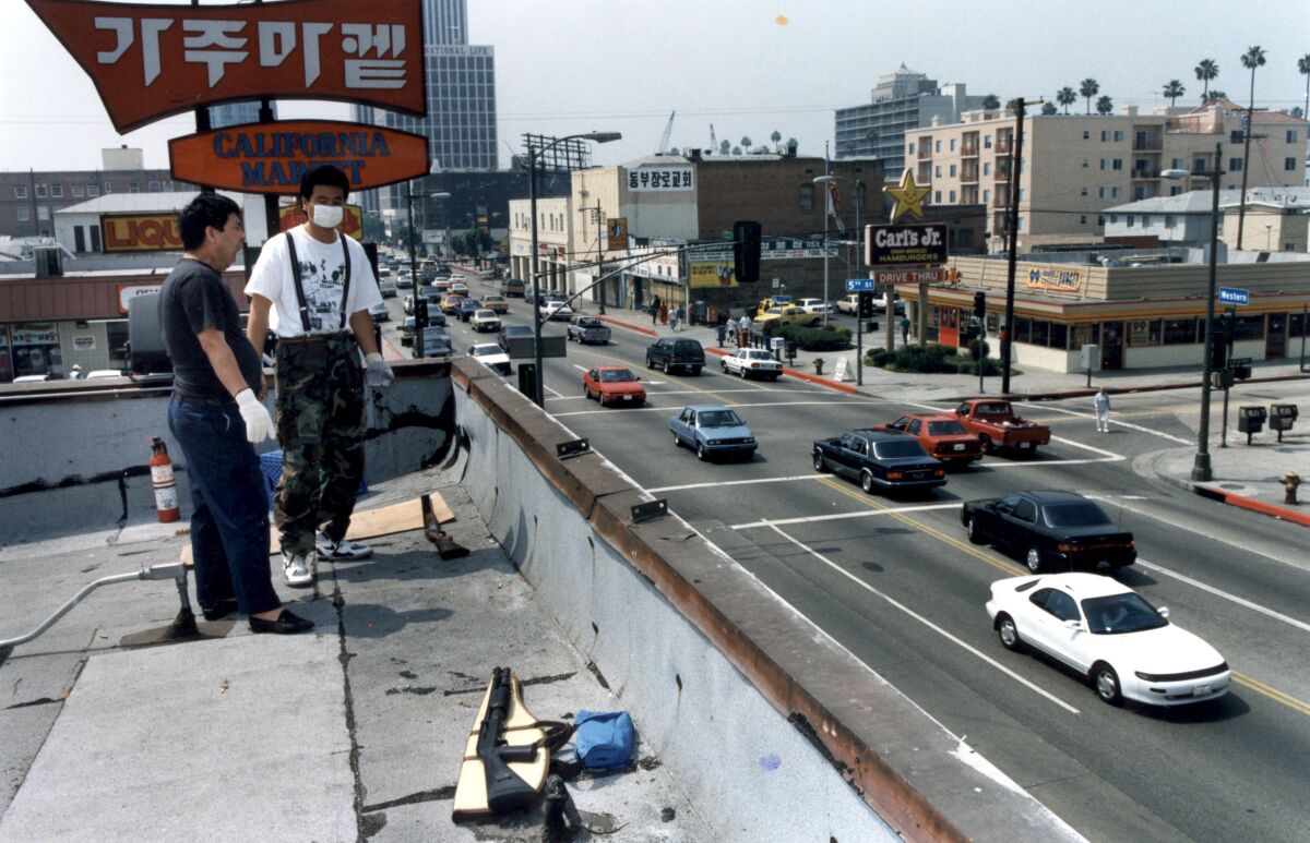 Two men with long guns nearby on the rooftop of a market in Koreatown in 1992