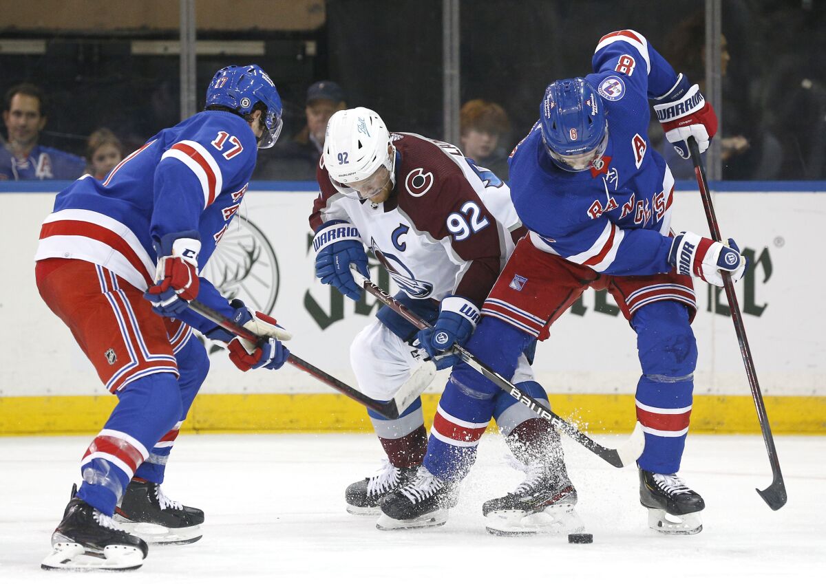 New York Rangers defenseman Jacob Trouba (8) and Colorado Avalanche left wing Gabriel Landeskog (92) battle for the puck during the second period of an NHL hockey game, Wednesday, Dec. 8, 2021, in New York. (AP Photo/Noah K. Murray)