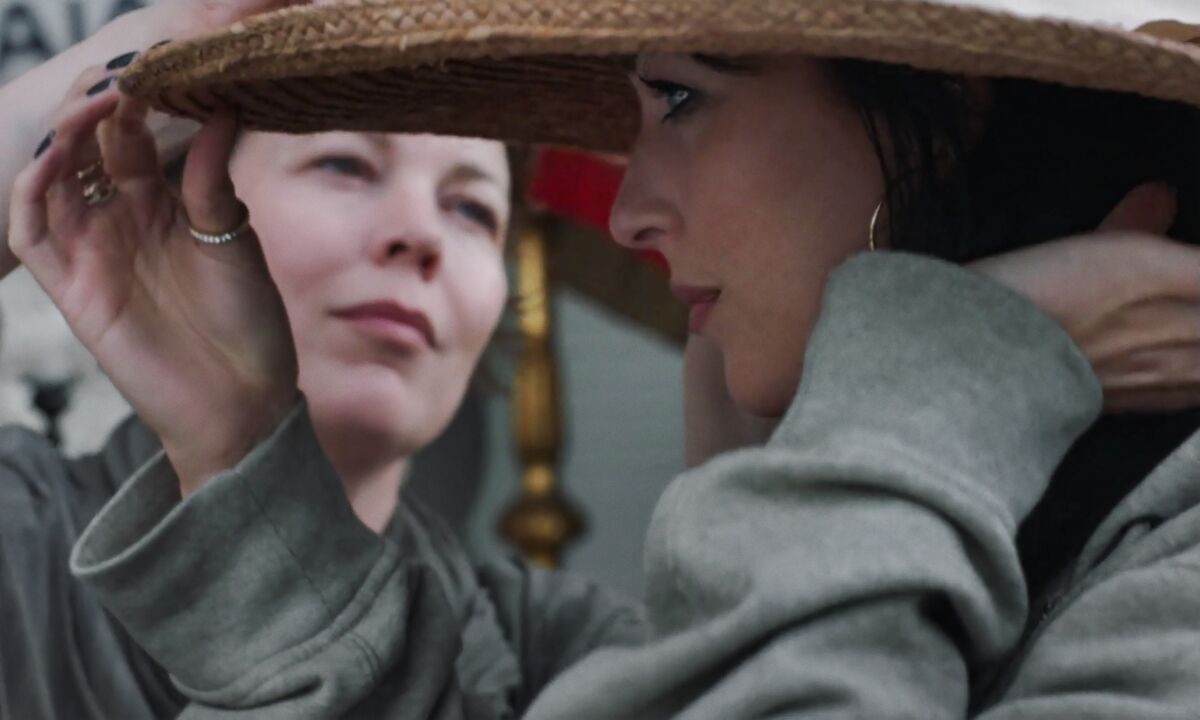 Two women, one wearing a hat and in profile