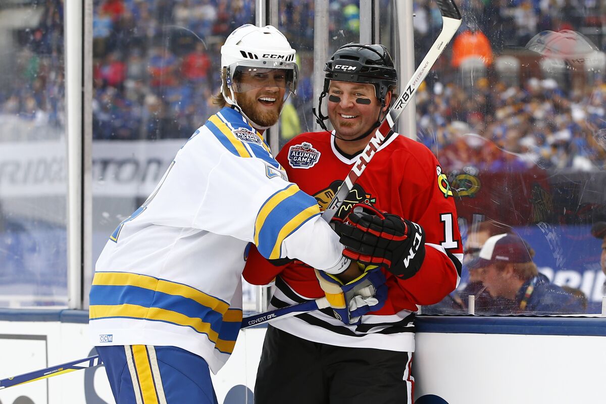 FILE - In this Dec. 31, 2016, file photo, former St. Louis Blues' Chris Pronger, left, laughs with former Chicago Blackhawks' Kyle Calder after a check during the Winter Classic alumni outdoor hockey game at Busch Stadium in St. Louis. At 46, Pronger has settled in the St. Louis suburbs and is helping his wife run a travel business. Playing air hockey is the closest thing the long-feared defenseman will have to his old sport any time soon. (AP Photo/Billy Hurst, File)