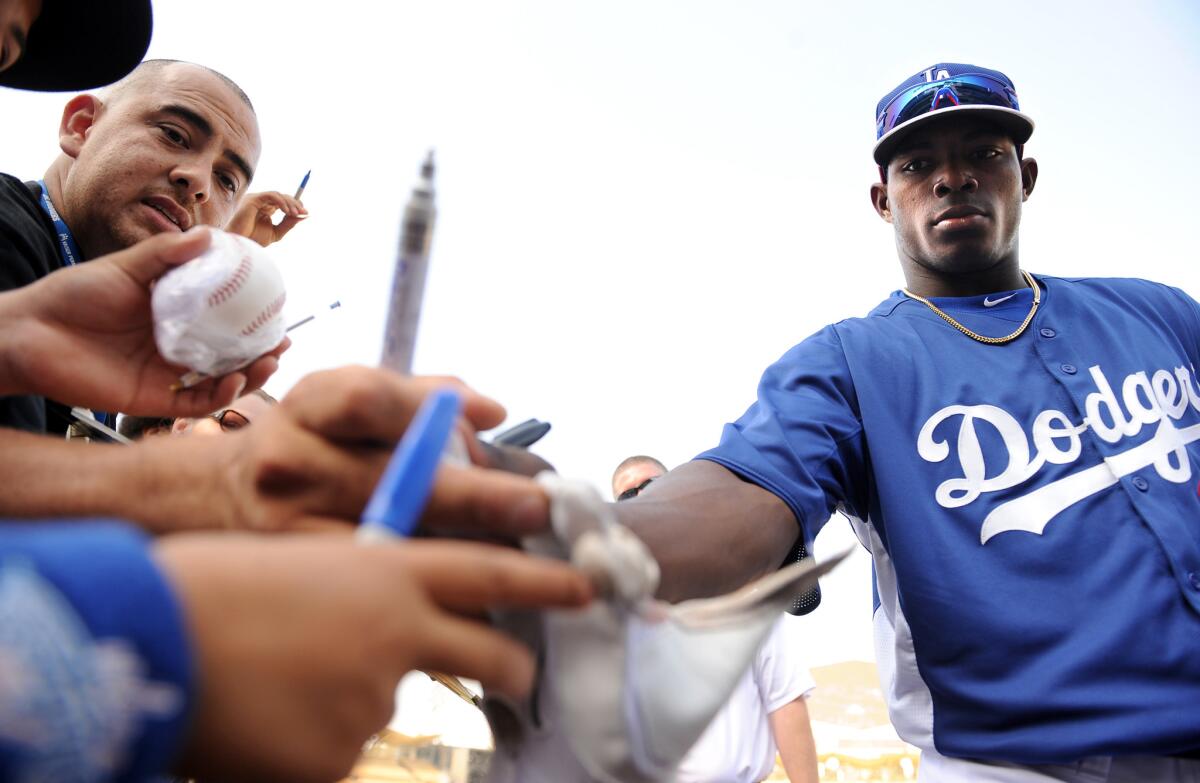 Dodgers right fielder Yasiel Puig gives away his batting glove to a fan before a game with the Braves at Dodger Stadium.