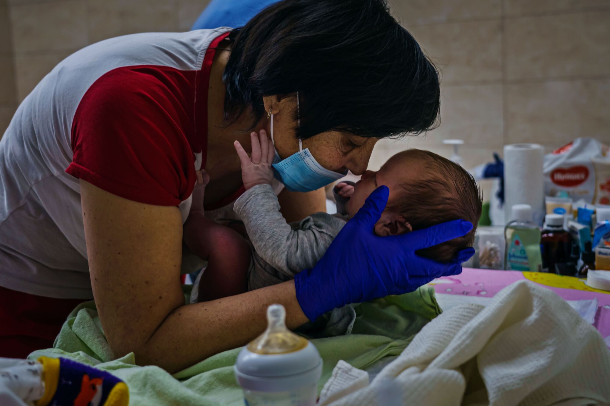 Nursing staff Svetlana Stetsiuk, tries to comfort an infant by rubbing their noses together, in a makeshift nursery