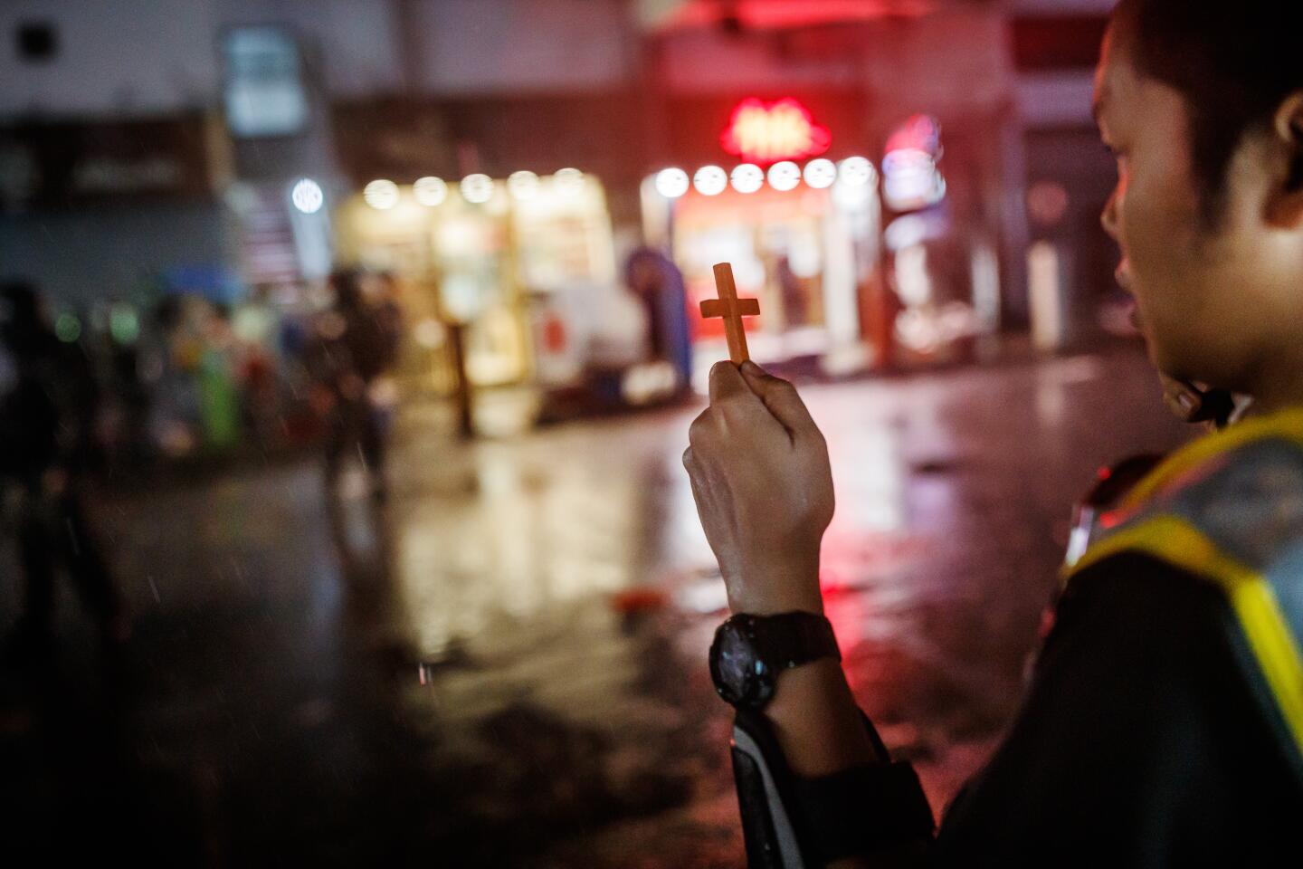 Pastor Roy Chan Hoi-hing, 38, leader of the Protect the Children, a community group who put themselves between the police and young Hongkongers protesting against the government, holds up a cross and prays for the protesters that were arrested by the police.