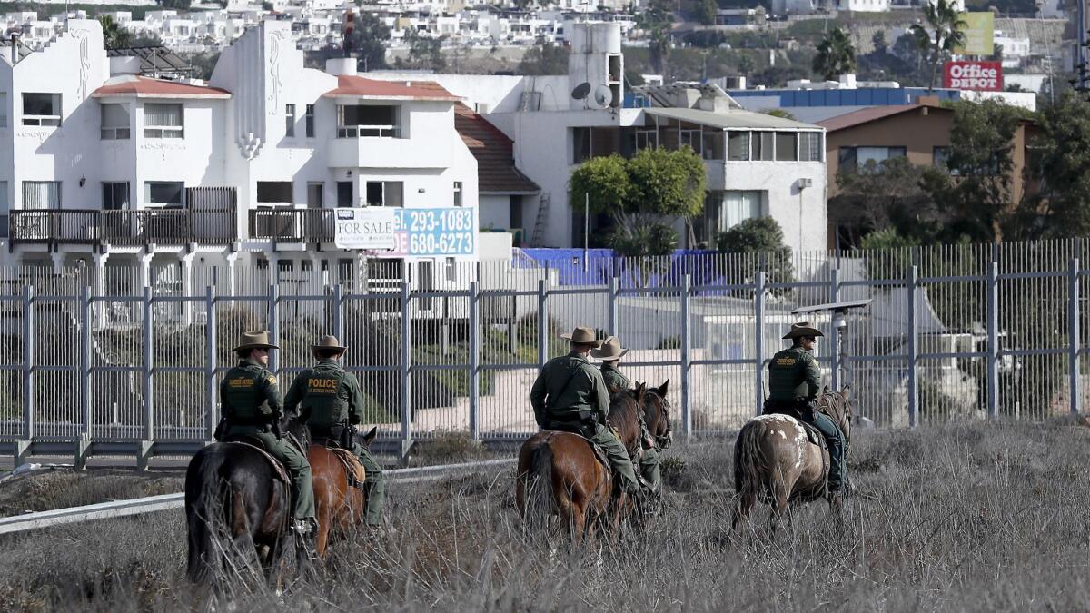 U.S. border officers patrol on horseback near the border fence in Imperial Beach.